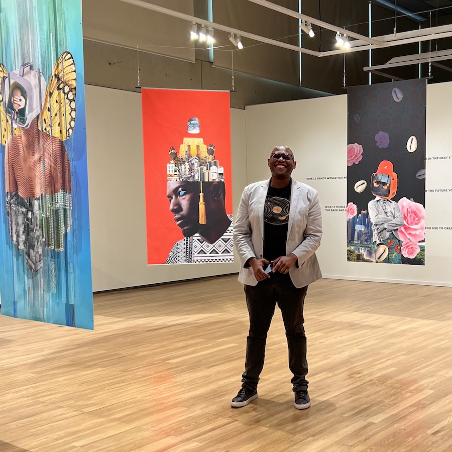 A Black man stands in the midst of banners depicting Afrofuturistic art
