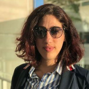 Headshot of a woman in sunglasses with should-length dark brown hair