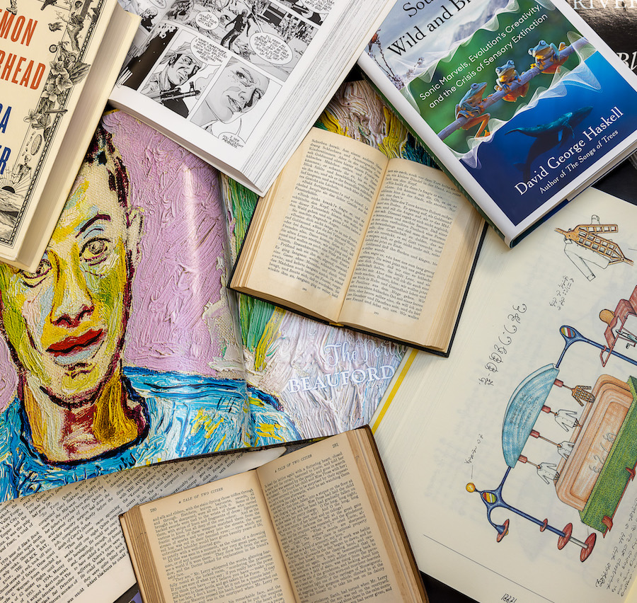 A number of open books and magazines lay in an overlapping pile. Prominent is a spread showing a portrait of a Black man by Beauford Delaney and an early modern illustration of a clothing machine.