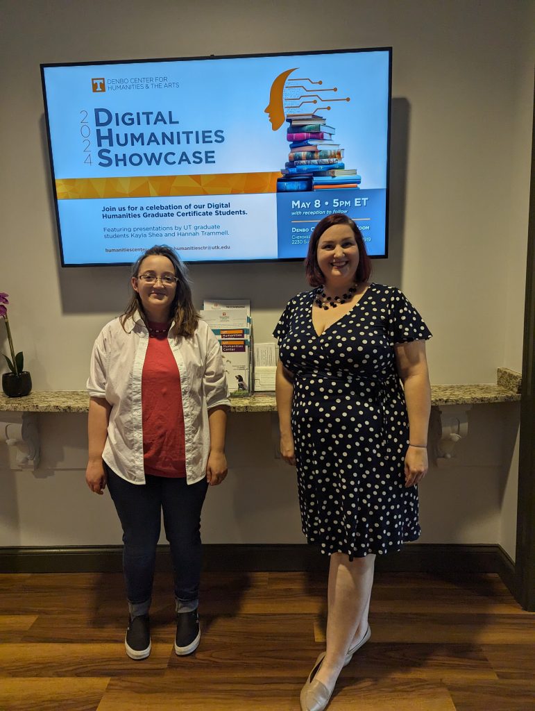 Two graduate students stand in front of a screen displaying the Digital Humanities Showcase publicity.